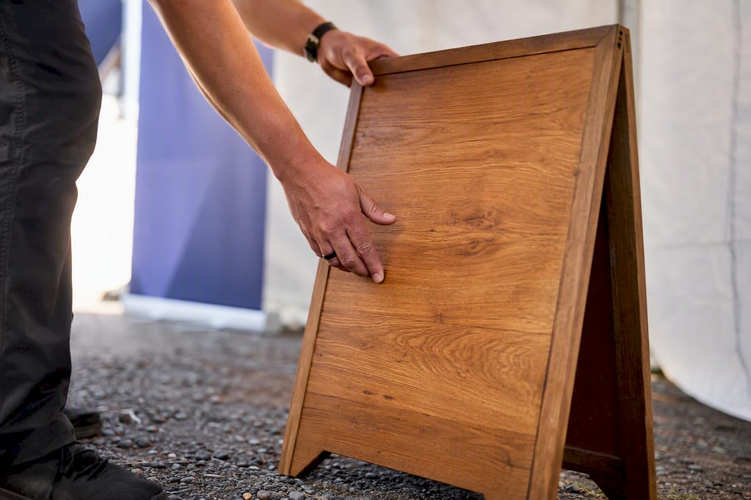 Hands placing outdoor A-frame shuttle sign