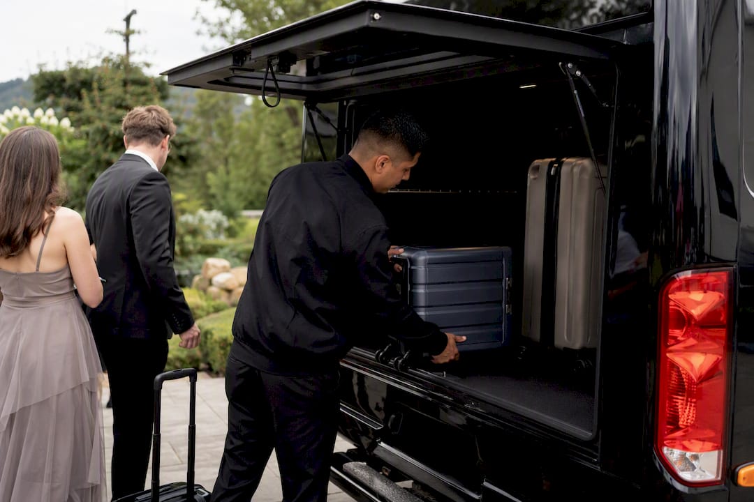 Driver loading luggage into guest shuttle van