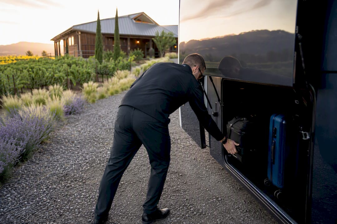 Hands loading luggage into shuttle at wedding venue
